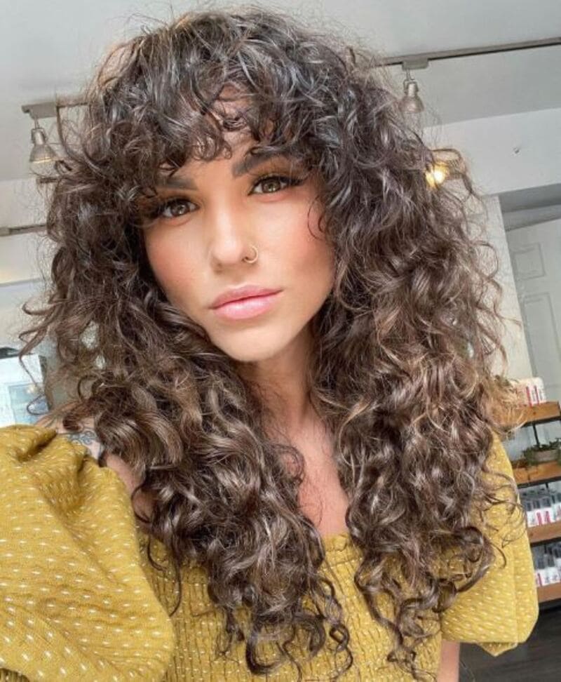 Curtain bangs on curly hair offer a unique and captivating look. (Source: Zohna)