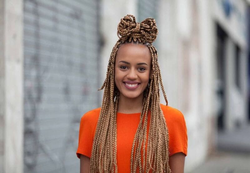 These honey blonde box braids styled in a high, loosely tied bun create a cute look. (Source: All Things Hair)